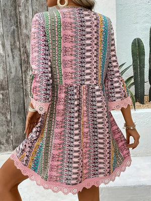 Bohemian pink printed v-neck dress with bell sleeves and lace trim.