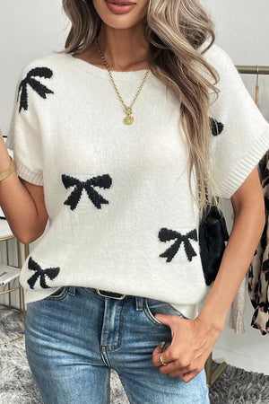 White knit tunic with black bow motif pattern, short sleeves, and crew neck.