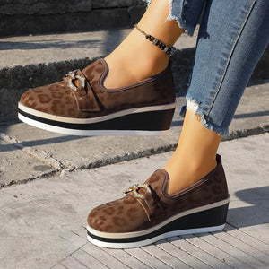 Brown leopard print wedge loafers with buckle detail and layered sole.