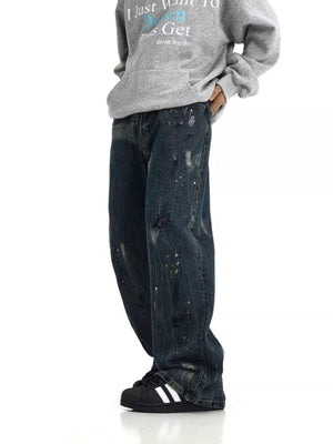 Distressed dark blue wide-leg cotton jeans with paint splatters and rips.