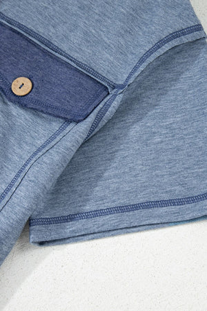 Denim-trimmed utility jumpsuit in dusty blue with a wooden button detail.