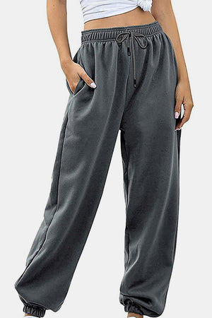 Relaxed-fit cuffed sweatpants in dark gray with a drawstring waist and side pockets.