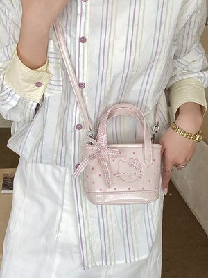Charming mini crossbody bag in blush pink with Hello Kitty graphic and bow detail.
