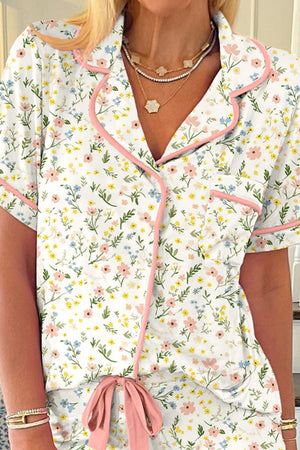 Pajama set with floral print, pink trim, button front, and bow detail.