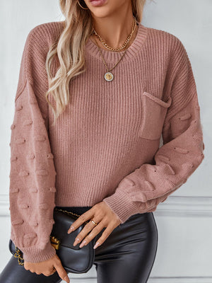 Dusty pink knit sweater with textured sleeve details and a chest pocket.