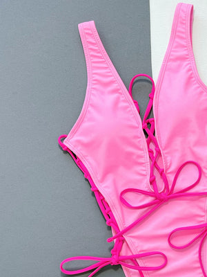 Pink lace-up plunge one-piece swimsuit with adjustable ties.