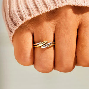 Two-tone gold intertwined open ring with twisted detail on a finger.