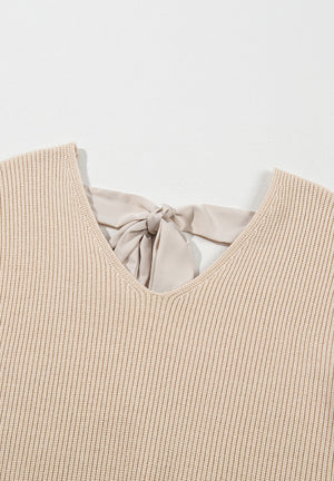 Beige ribbed knit sweater with a V-neck and a satin bow detail at the back.