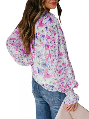 Vibrant floral print blouse with tie detail, long sleeves, and smocked cuffs.