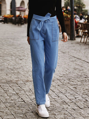 Belted high-waist light wash denim barrel trousers with tie waist and patch pockets.