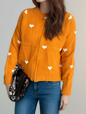 Tangerine zip-through knit cardigan with white heart print, crew neck, and ribbed cuffs.