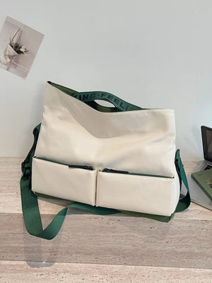 Ivory Oxford cloth travel bag with green strap and dual front zip pockets.
