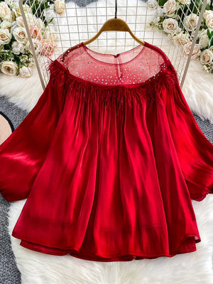 Red sheer blouse with rhinestone embellishments and feather trim detail.