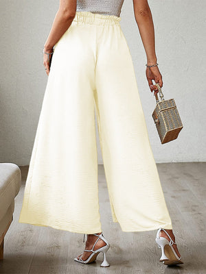 Pleated palazzo pants in pastel yellow with a high waist, wide leg, and side slit.