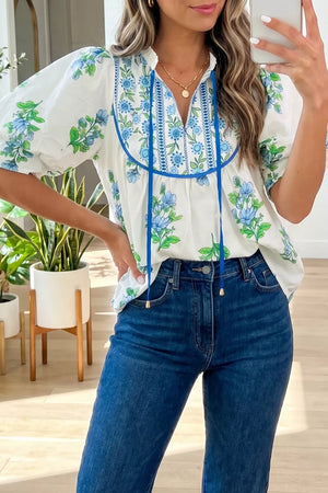 White floral tie-neck shirt with blue embroidery and puff sleeves