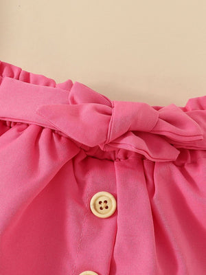 Pink baby set with ruffled waist, bow detail, and wood buttons.