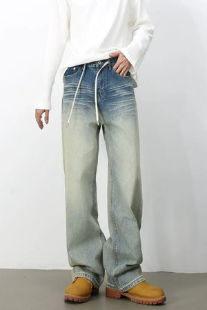 Faded wash wide-leg jeans with drawstring waist and distressed details.