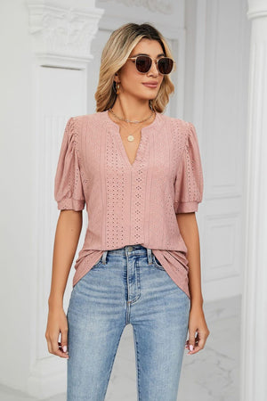 Pink perforated puff sleeve blouse with keyhole neckline and textured pattern.