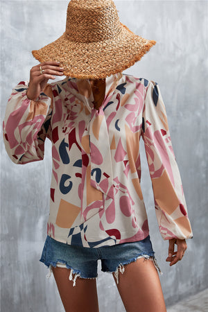 Abstract print pussy bow blouse with balloon sleeves in pink and cream with geometric shapes.