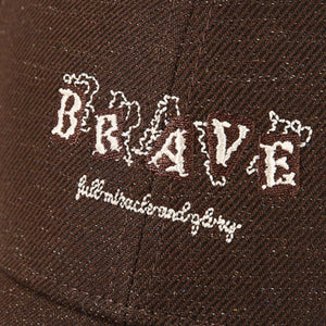 Brown cotton baseball cap with white embroidered "BRAVE" text and smaller script below.