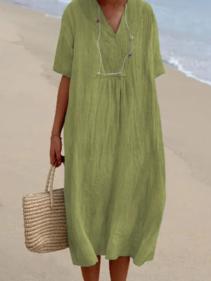 Light green V-neck casual midi dress with short sleeves and a relaxed fit, styled with a straw bag.