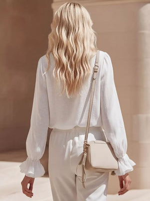 White maternity shirt with ruffled cuffs and V-neck detail.