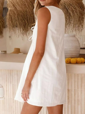White tie-front mini dress with a sleeveless A-line cut and subtle texture.