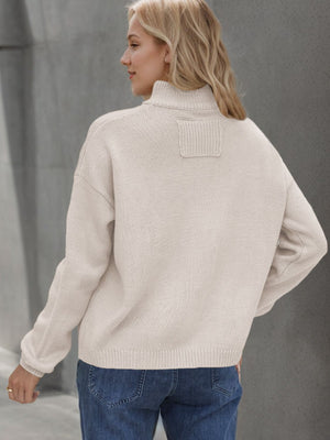Cream acrylic knit stand collar cardigan with ribbed details and patch on back.