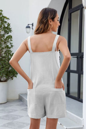 White linen romper with square neck, bow straps, and cuffed shorts.