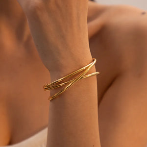Gold-tone open cuff bracelet with intertwined thin bands.