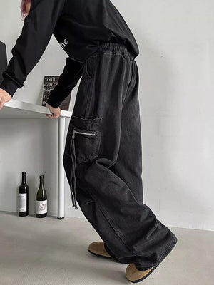 Relaxed fit black denim cargo jeans with drawstring waist and zippered pocket detail.