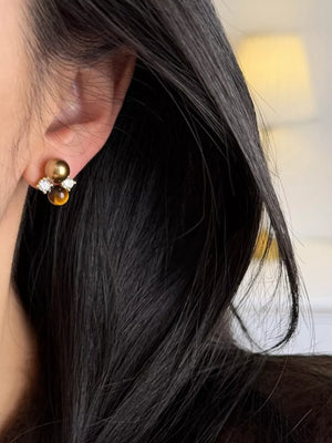 Spherical tiger eye stone stud earrings with clear accents and a gold bead cluster.