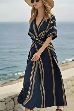 Dark navy wrap maxi dress with gold stripes, V-neck, short sleeves, and flowing skirt.