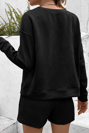 Black textured geometric lounge set with crew neck sweatshirt and shorts.