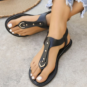 Black t-strap sandals with ankle support, gold buckle detail, and stud accents.