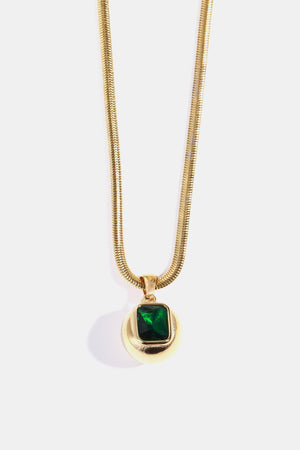 Gold necklace with a round pendant featuring a square dark green stone.