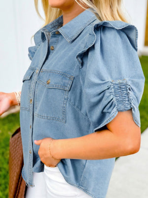 Light wash denim button-down shirt with ruffled shoulders and ruched sleeves.