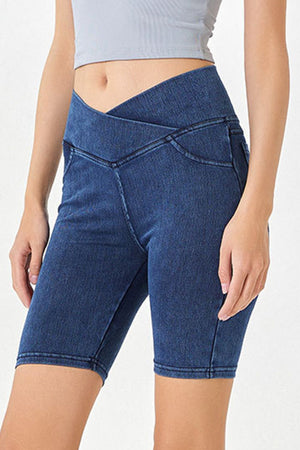 Denim bermuda shorts in medium wash with a crisscross waistband and asymmetrical detail.