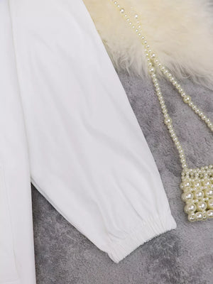White midi dress with cuffed sleeves and elasticized cuffs.