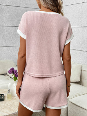 Pink ribbed knit two-piece set with white trim, short sleeves, and shorts.