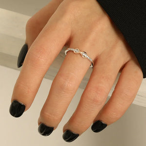 Infinity knot ring with diamonds in silver and blush pink accents.