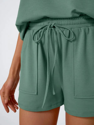 Green drawstring shorts with pockets and a matching cap-sleeve top.