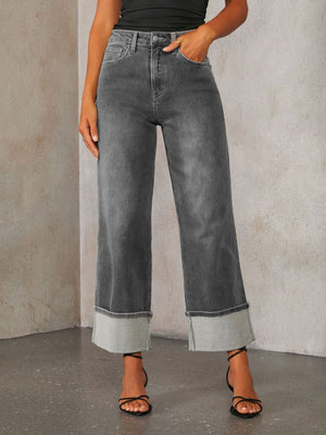 Dark wash denim jeans with wide legs and large folded cuffs.