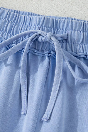 Light blue cotton drawstring shorts with ruffled waist detail and tie.