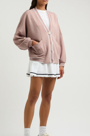 Dusty pink cocoon cardigan with white trim and buttons, featuring pockets and a relaxed fit.