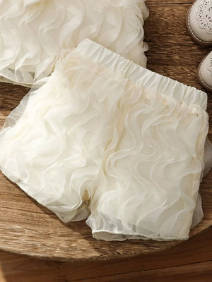 Cream ruffled baby shorts with elastic waist and sheer overlay.