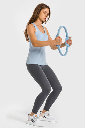 Gray high-waist performance leggings with ankle length, worn by a woman holding a blue pilates ring.