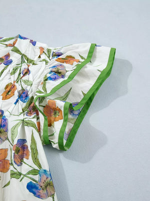 Cotton shirt with vibrant floral print, ruffled sleeves, and green trim.
