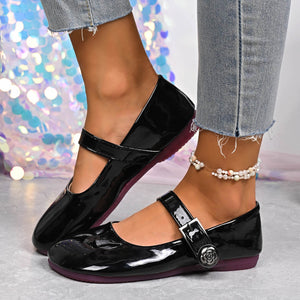 Black patent buckle strap Mary Jane loafers with rose detail and purple sole.