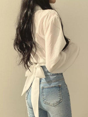White long sleeve maternity shirt with knot front detail and buttoned cuffs.